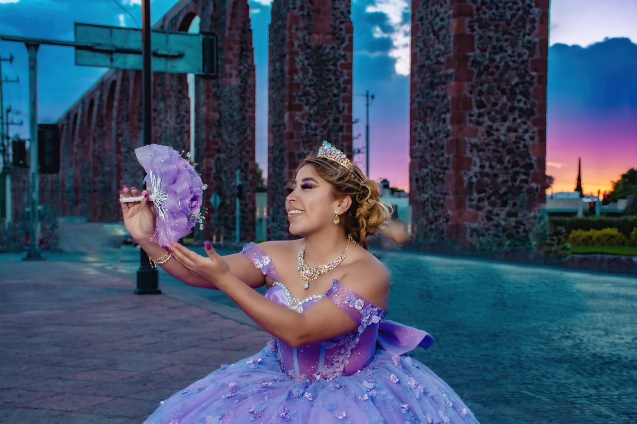 Una mujer con un vestido morado sostiene un abanico.