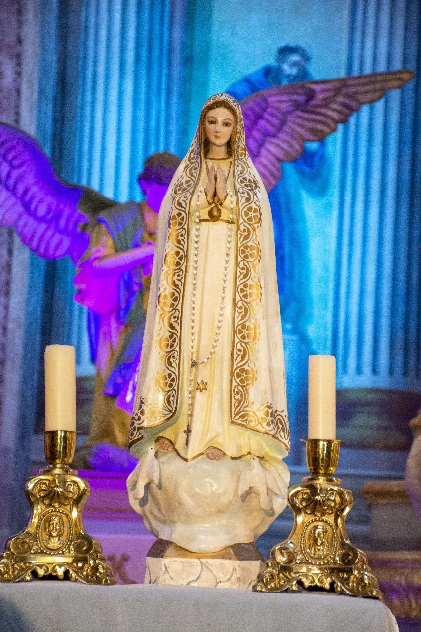 Una estatua de la Virgen María está sobre una mesa con velas.