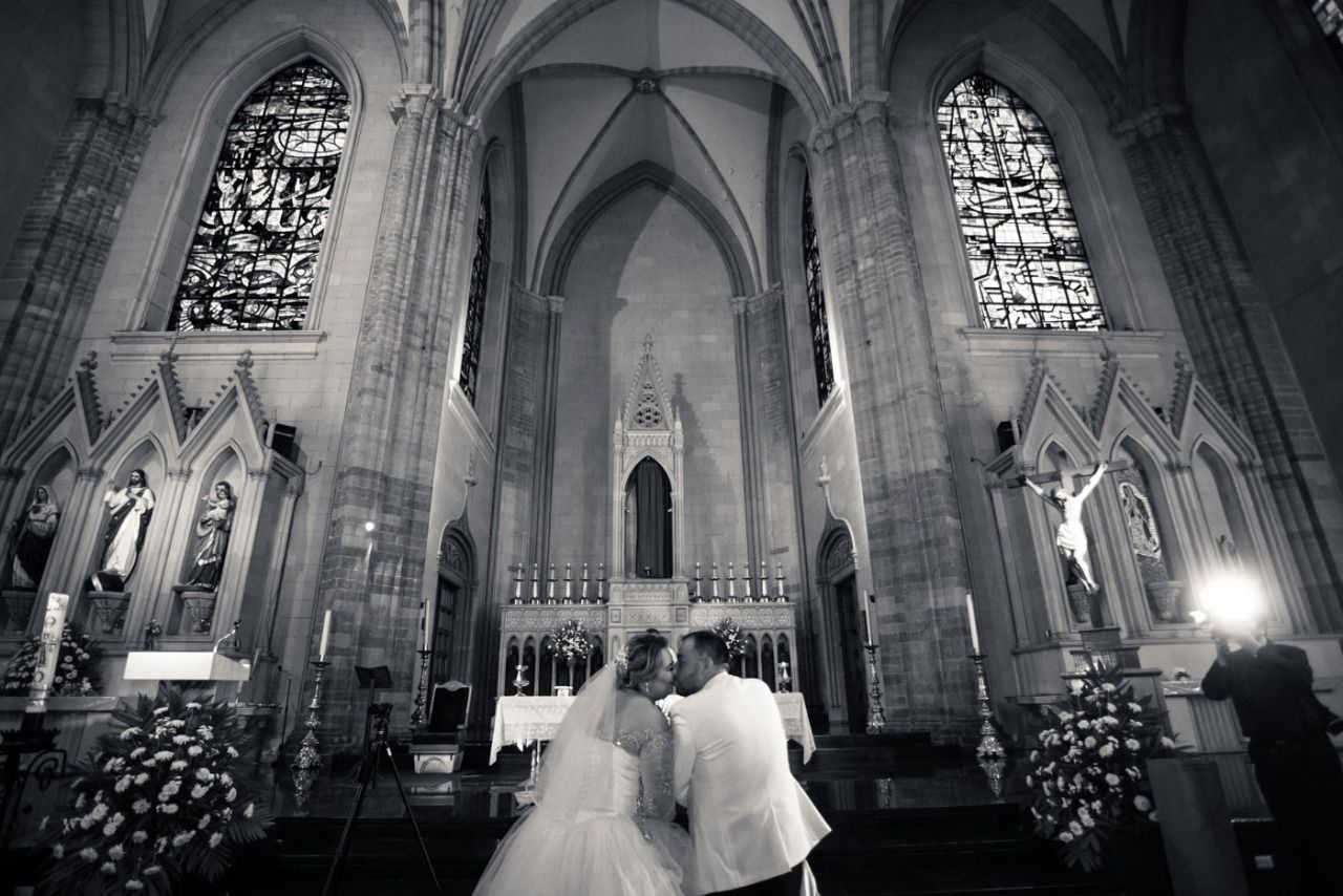 Una novia y un novio se besan en una iglesia.