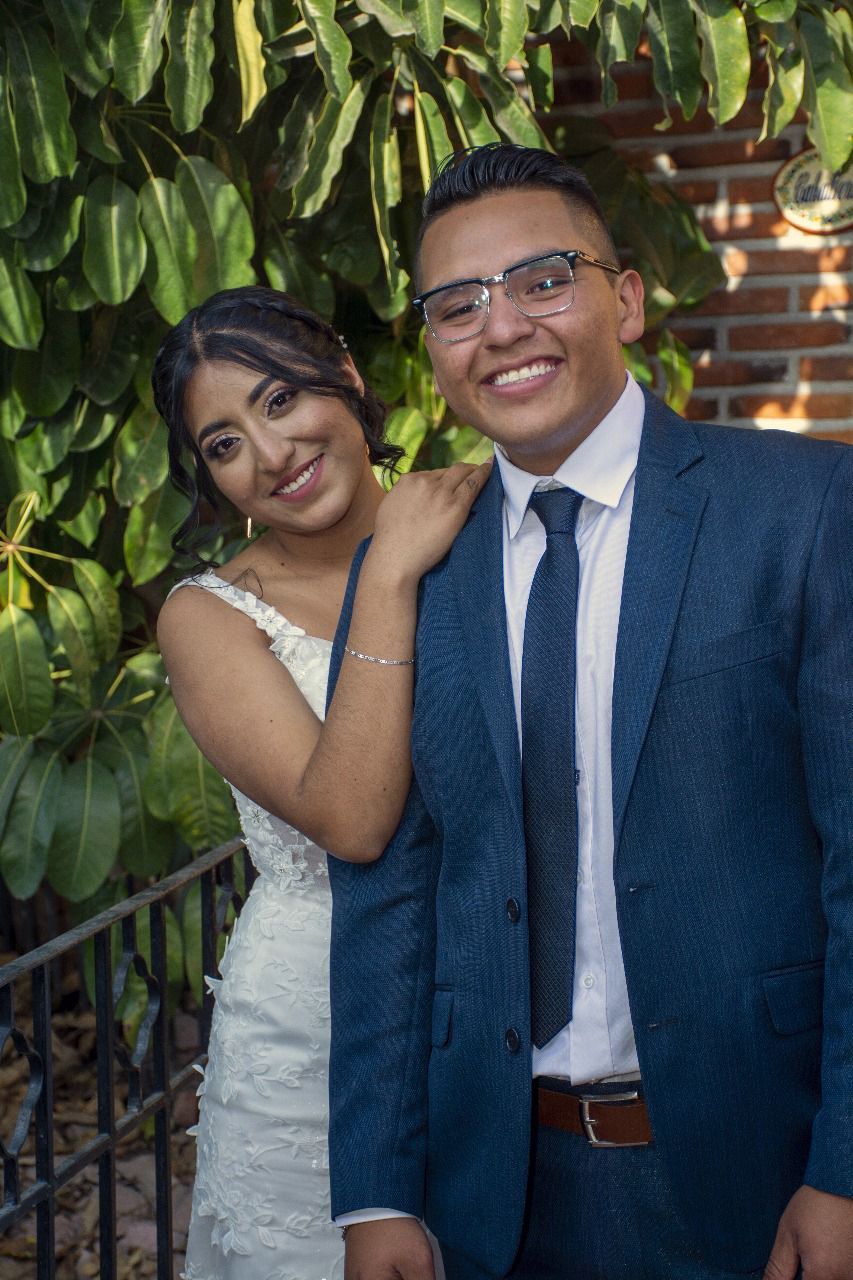 Un hombre con traje y corbata está de pie junto a una mujer con un vestido de novia.