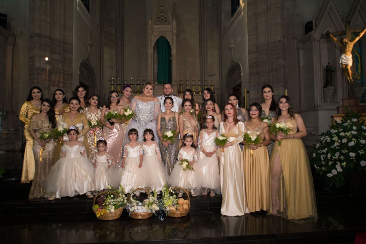 Una novia y un novio posan para una fotografía con sus damas de honor y niñas de las flores en una iglesia.