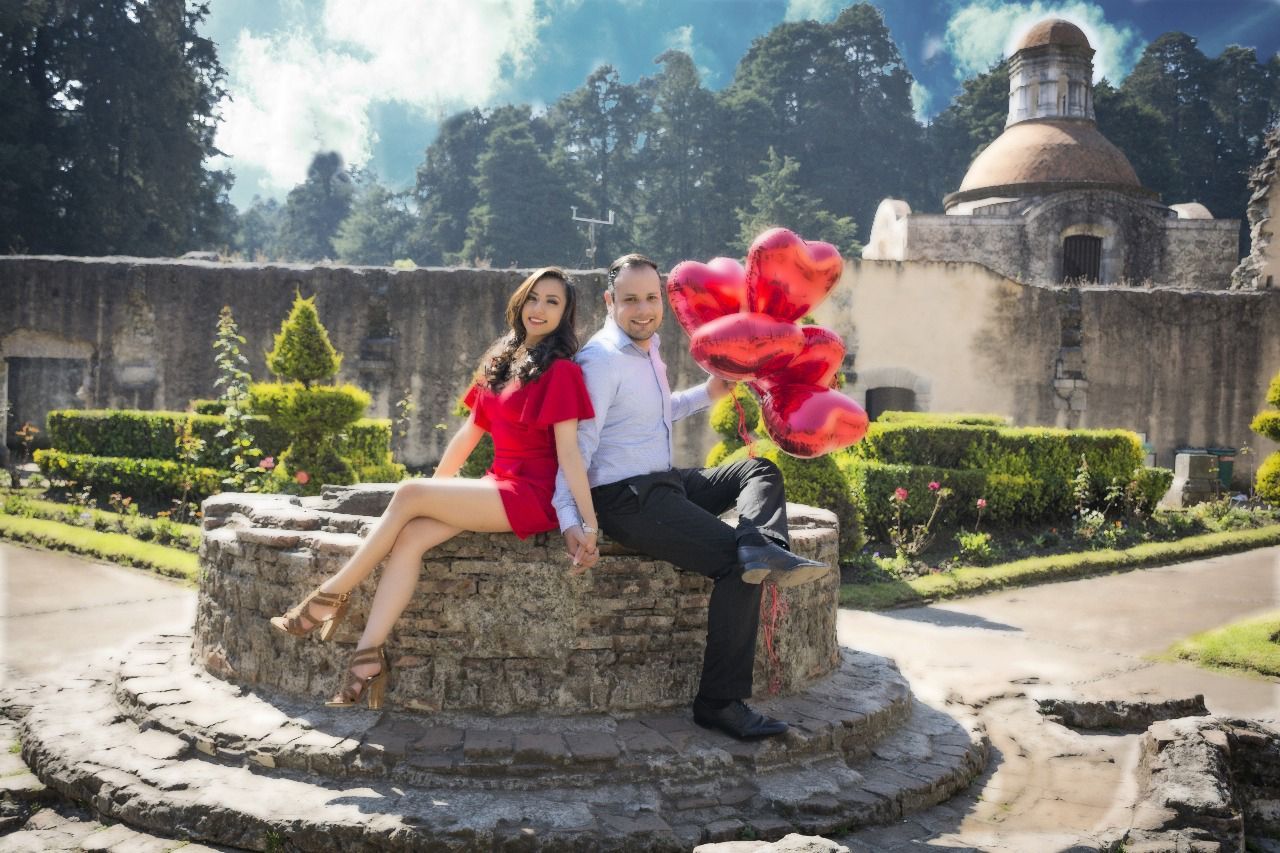 Un hombre y una mujer están sentados en un muro de piedra sosteniendo globos.