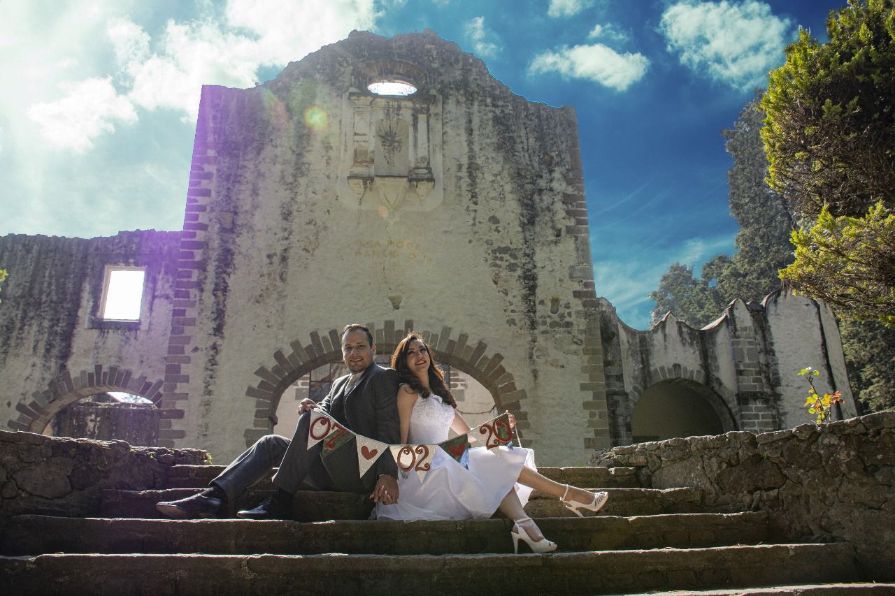 Una novia y un novio están sentados en las escaleras de un edificio antiguo.