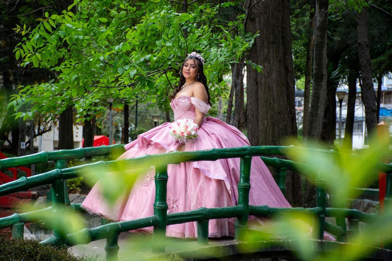 Una mujer con un vestido rosa está parada en un puente.