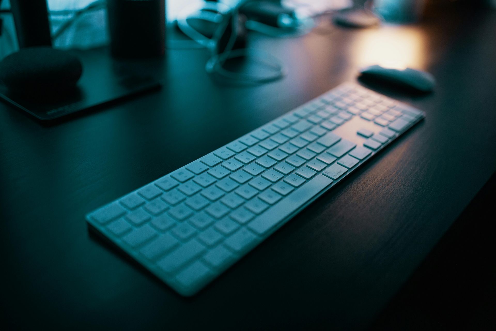 White keyboard and mouse in front of a computer on a desk at dusk