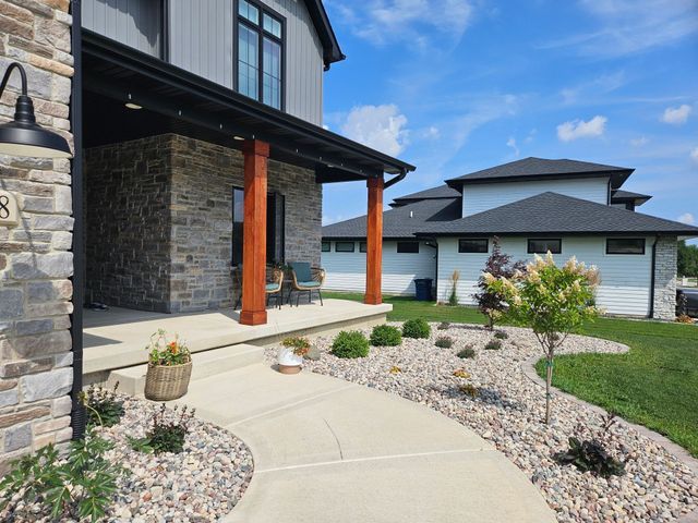 Exterior of modern home with stone and wood accents; walkway through landscaped yard.
