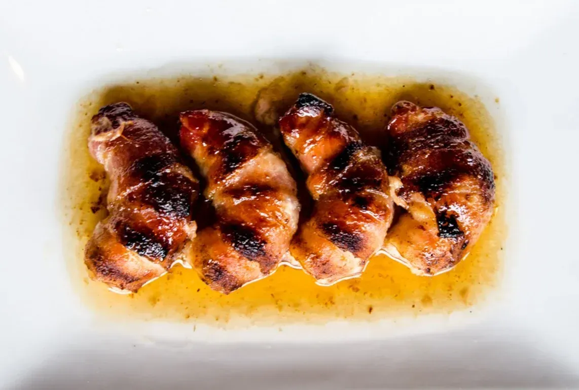 A white plate topped with grilled meat and sauce.