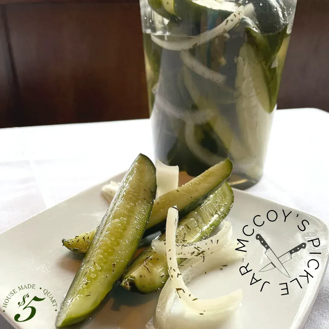 A plate of pickles sits next to a glass of pickles