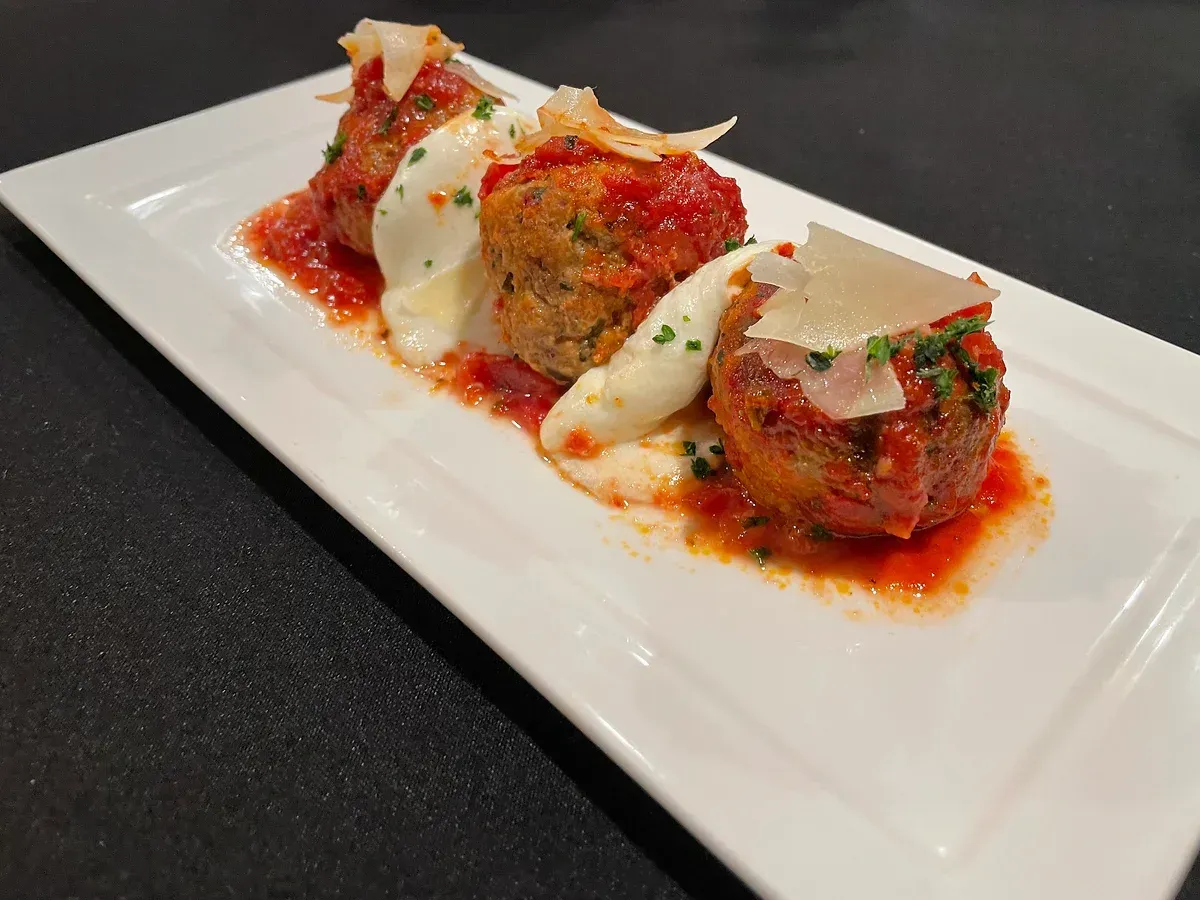 A white plate topped with meatballs and sauce on a table.