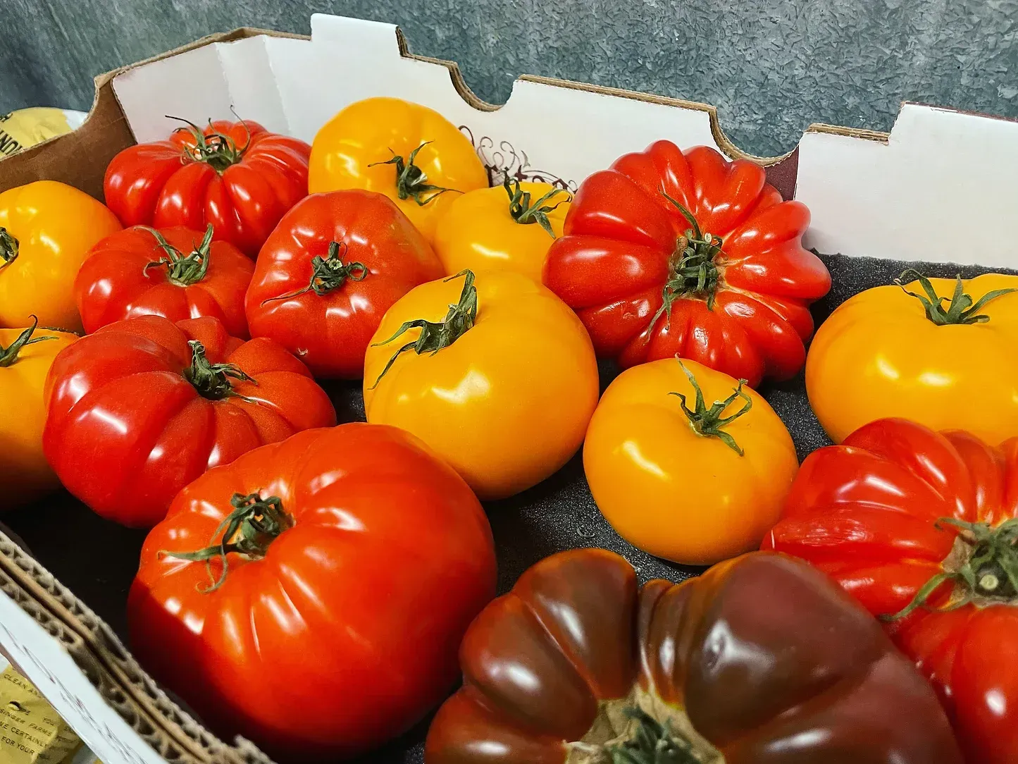 A cardboard box filled with red and yellow tomatoes