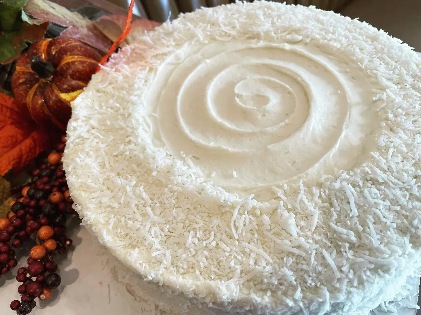 A white cake with coconut on top is sitting on a table.