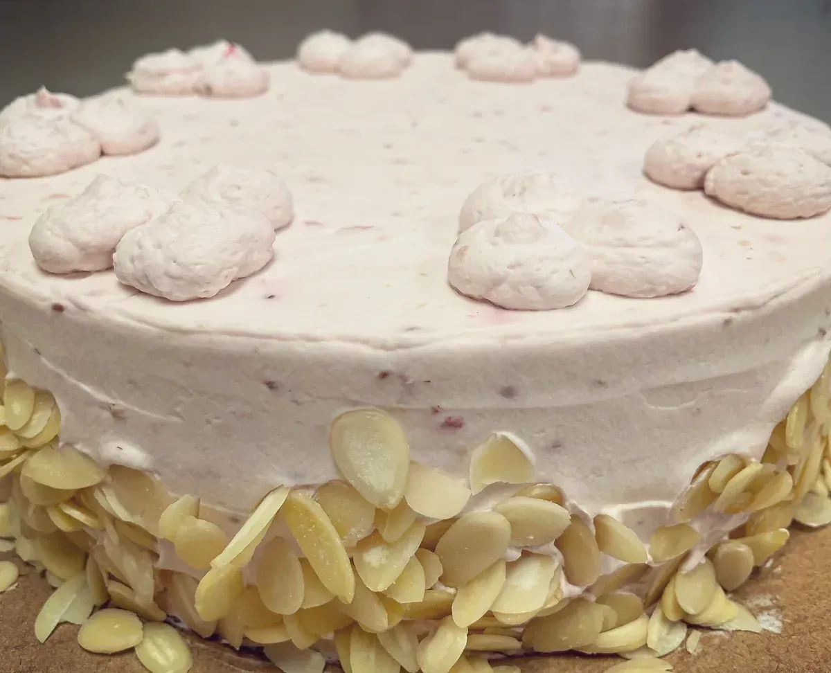 A cake with pink frosting and almonds on top