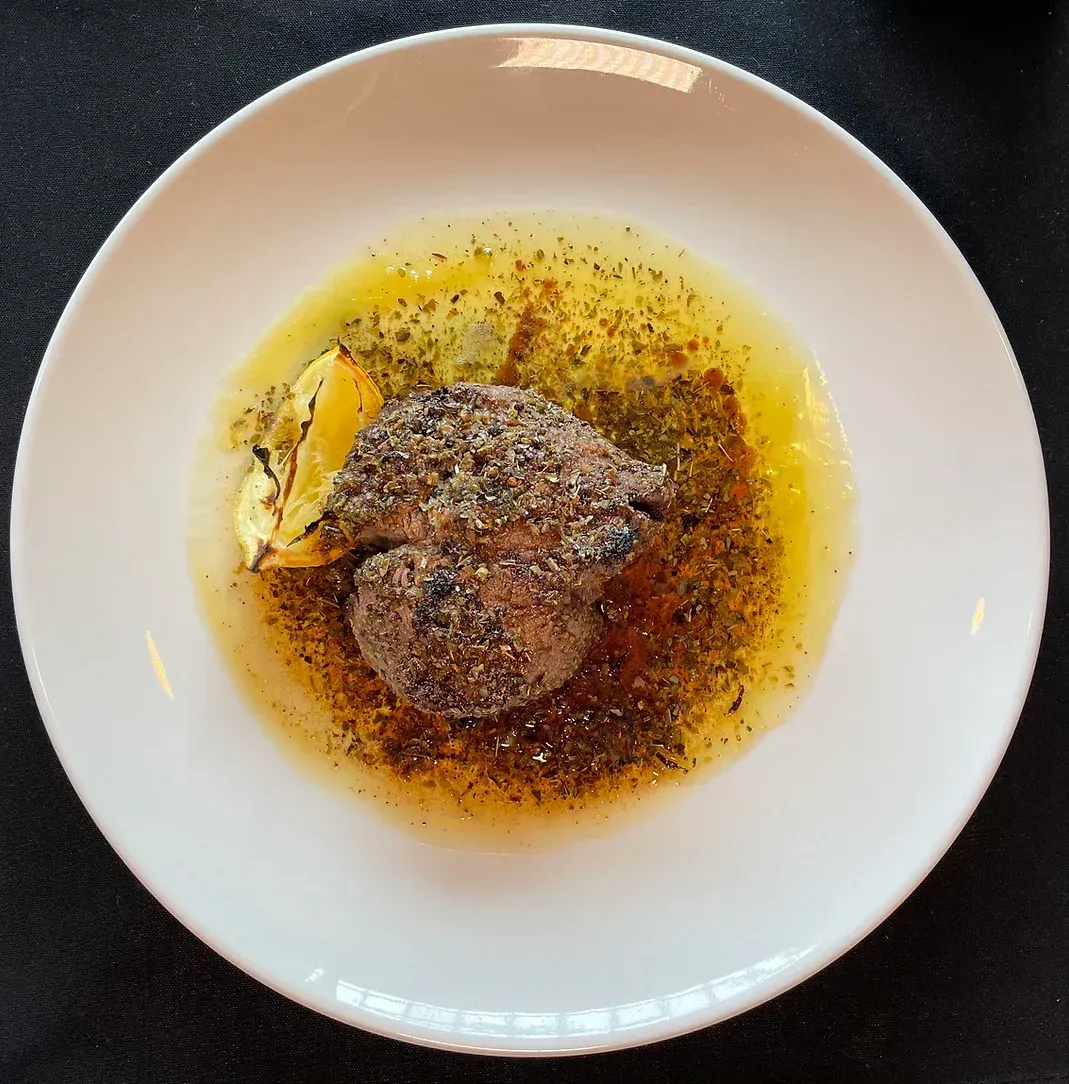 A white plate with a piece of meat on it