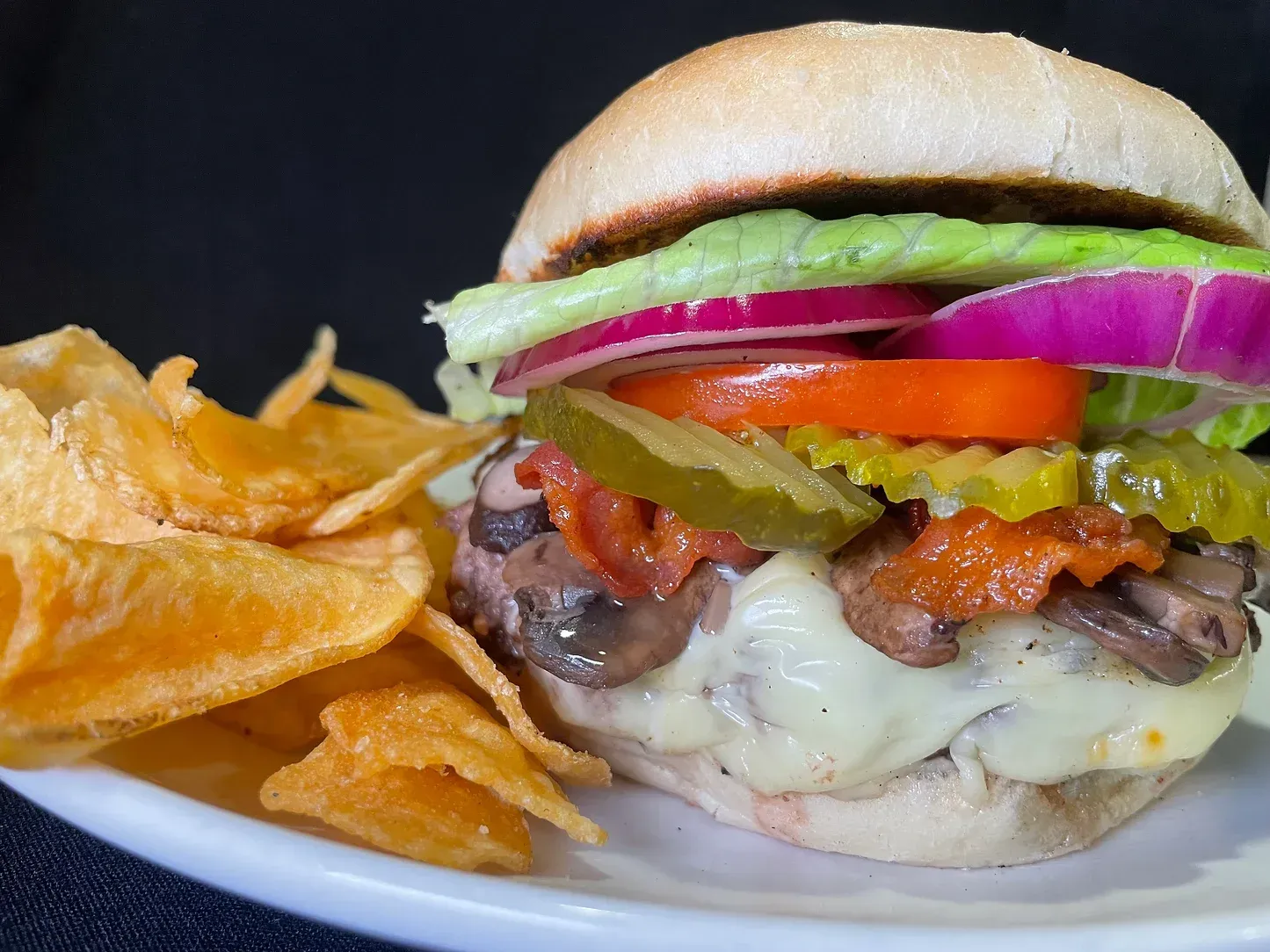 A close up of a hamburger on a plate with chips