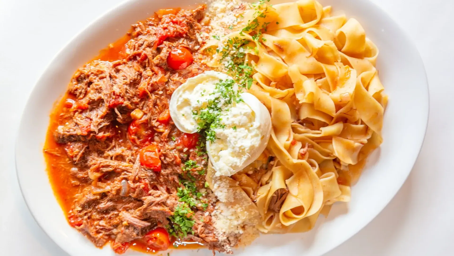 A white plate topped with meat and pasta on a table.