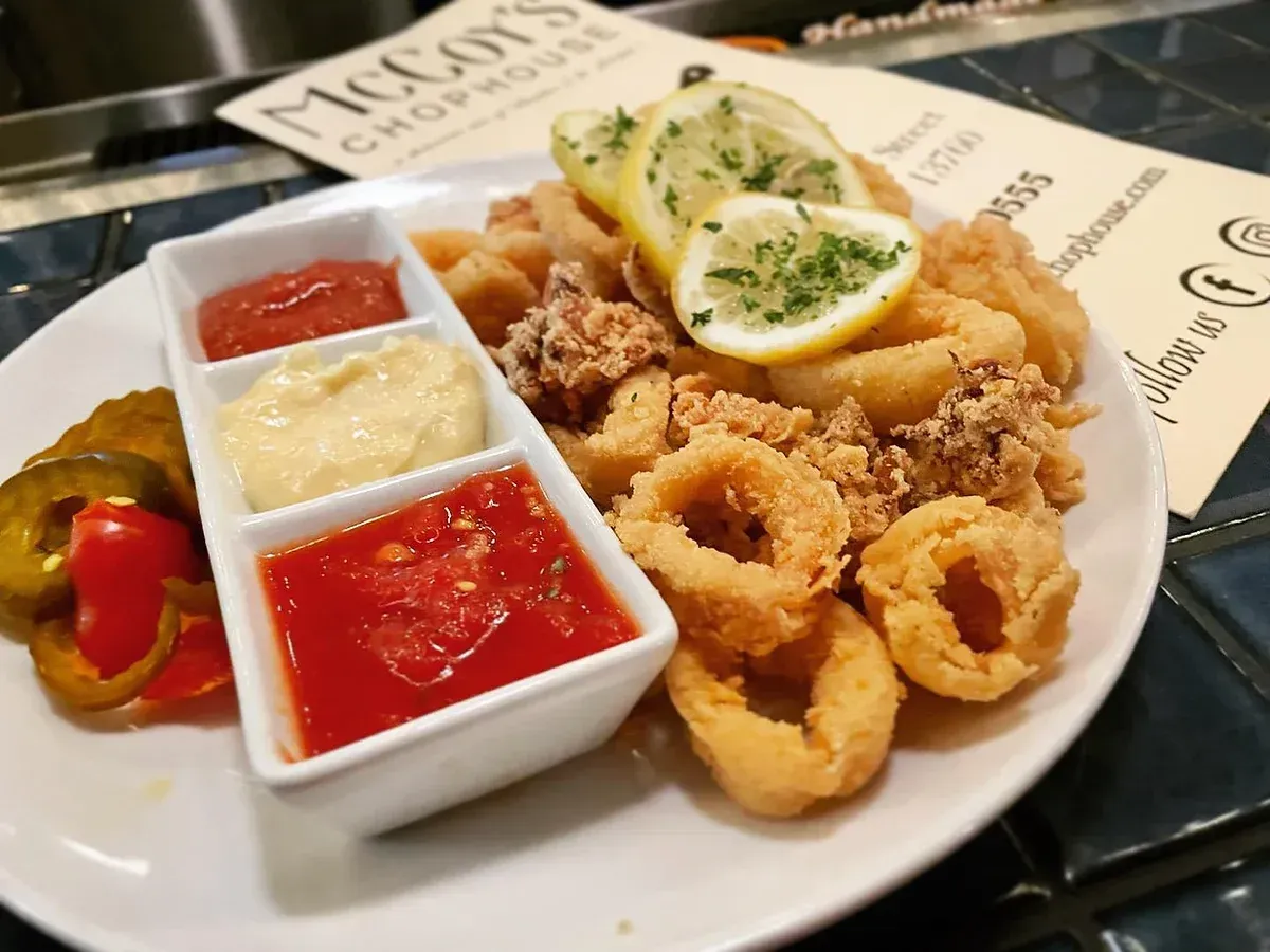 A white plate topped with fried calamari and sauces