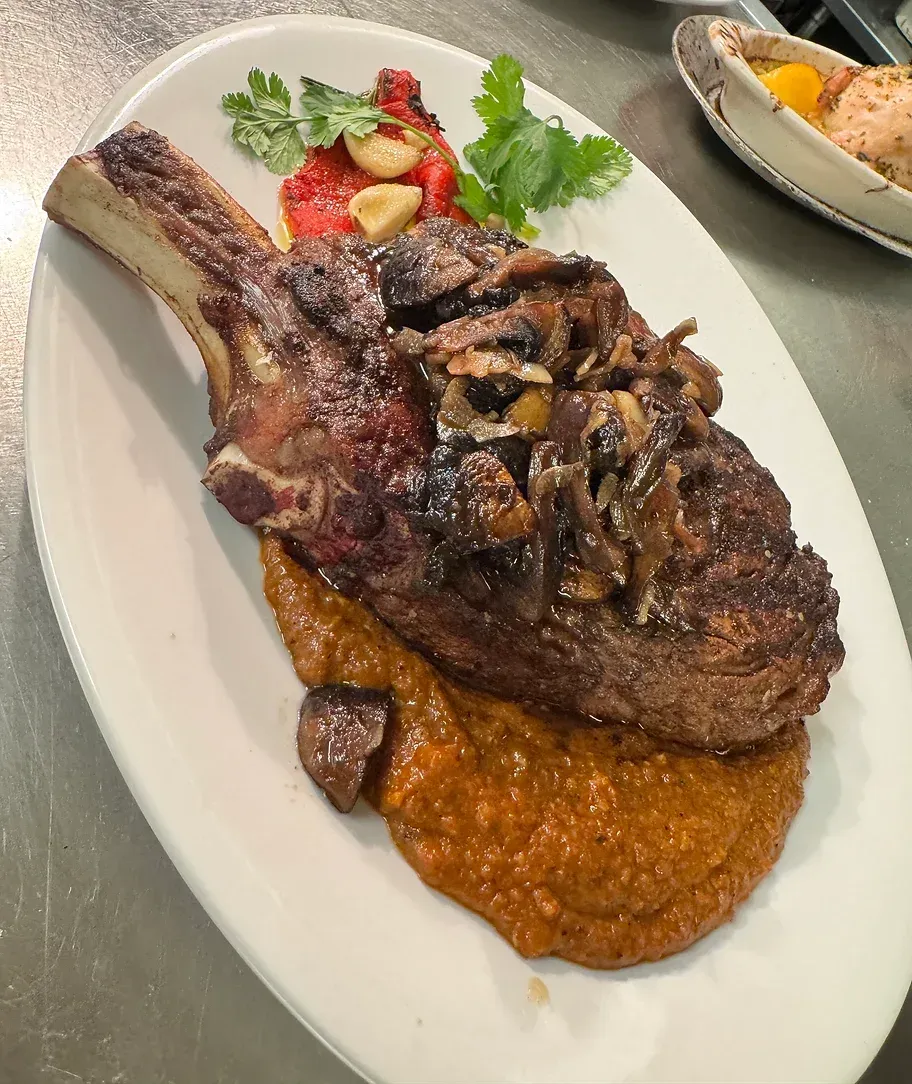 A white plate topped with a steak and vegetables on a table.