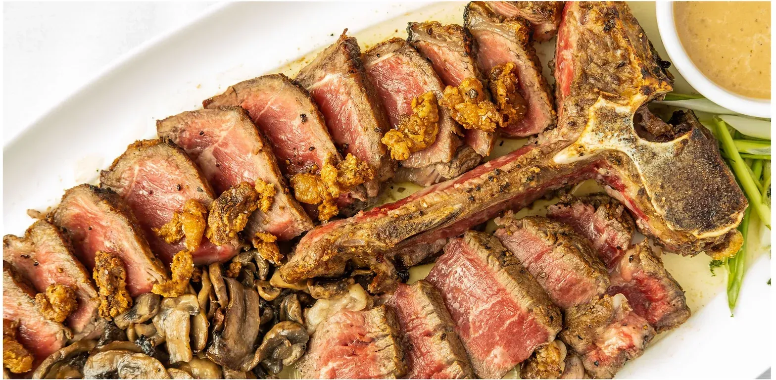 A white plate topped with sliced steak , mushrooms and green beans.