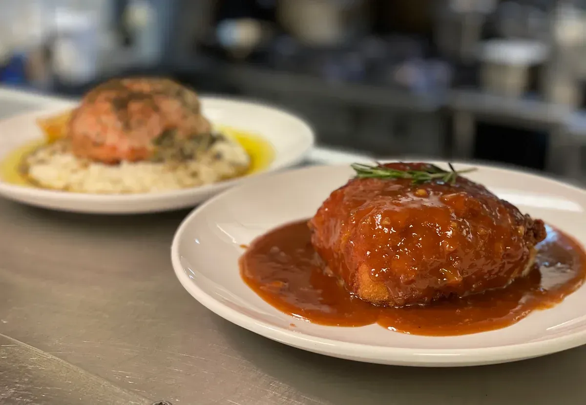 Two plates of food with sauce on them are on a table.