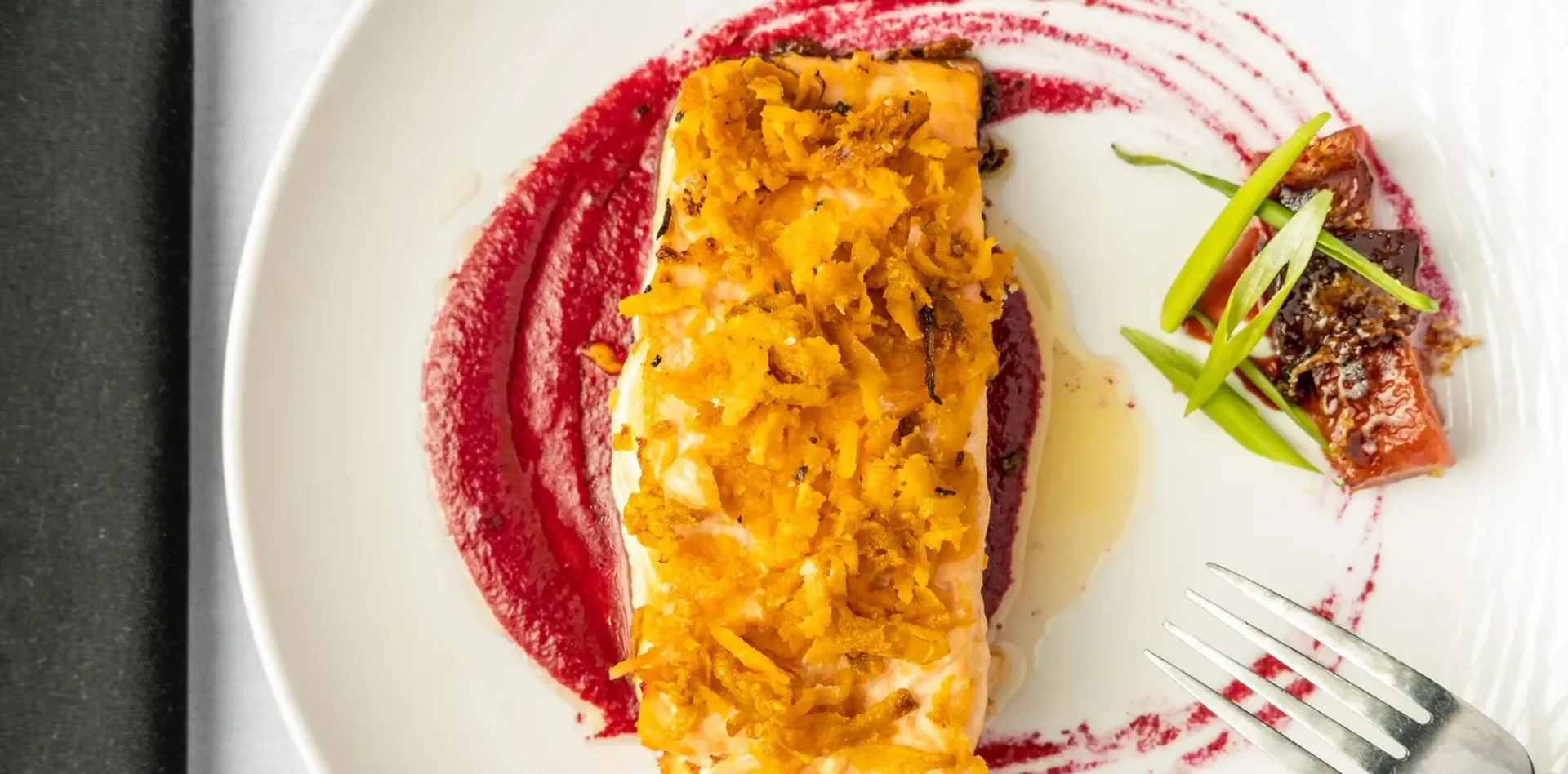 A close up of a plate of food with a fork on a table.