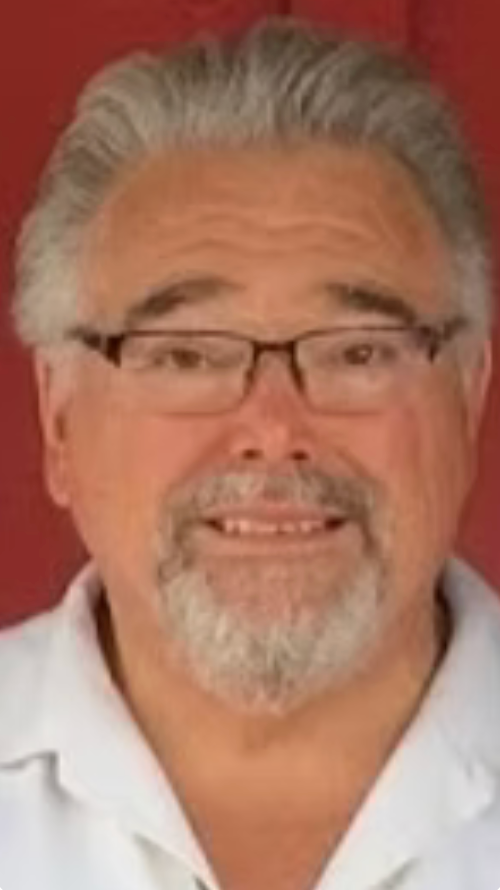 A man with glasses and a beard is smiling for the camera.