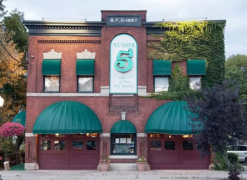 A brick building with green awnings and a sign that says number 5