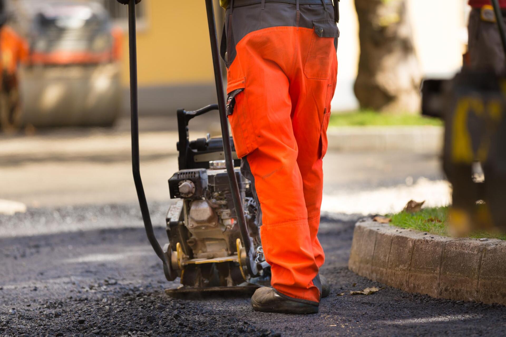 worker flattens the asphalt