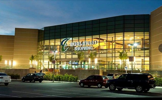 Exterior do Boulevard Stadium ao entardecer, com a fachada de vidro iluminada e carros estacionados em frente.