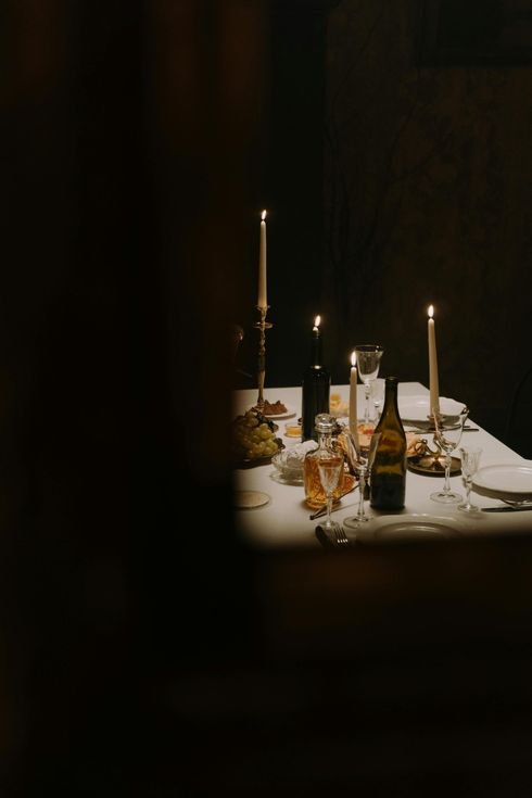 A table with a bottle of wine and candles on it in a dark room.