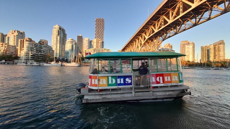 AquaBus ferry on water with downtown Vancouver and bridge in the background.