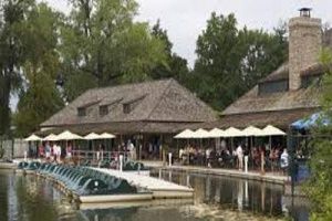 Restaurant on lake with outdoor seating, wooden dock, and paddle boats.