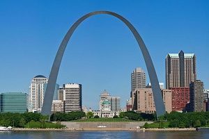 Gateway Arch in St. Louis, Missouri, a large silver arch against a blue sky, with city buildings in the background.
