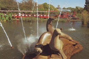 Sculptures of seals in a pond with water fountains; train in background.