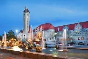 Fountain in front of Union Station, St. Louis, Missouri. Stone building, clock tower, water spouts, bronze sculptures, dusk.