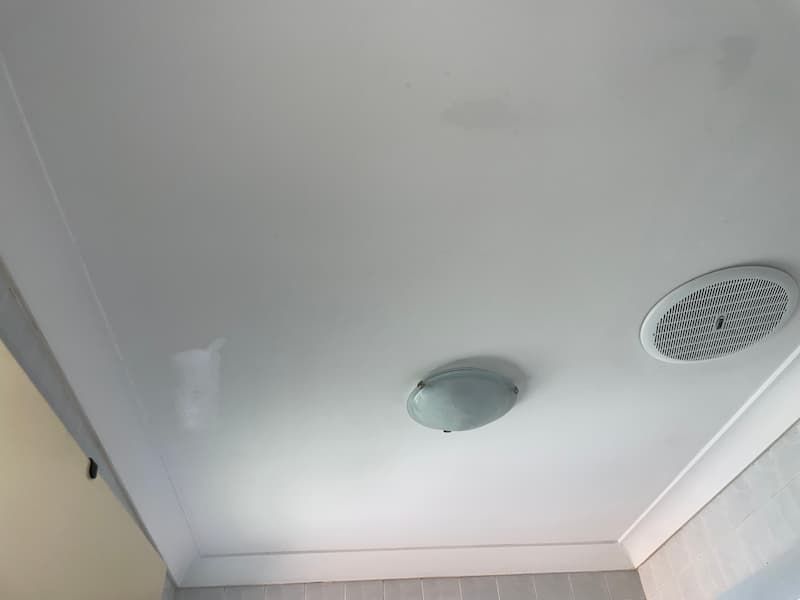 White ceiling with a recessed light and air vent.