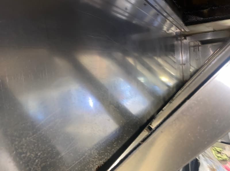 Stainless steel interior, likely a commercial kitchen. Reflective surfaces show angles and details.