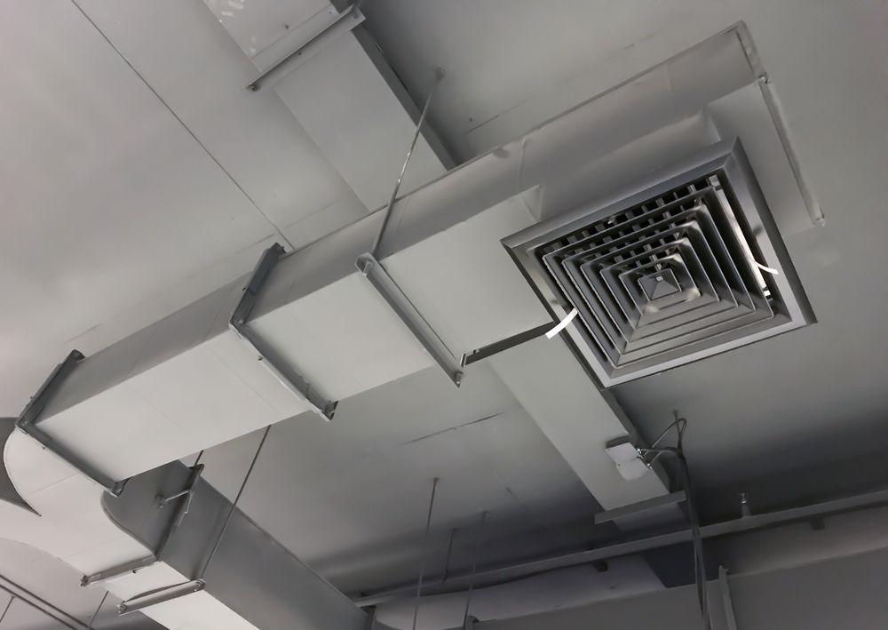 Gray air ducts and vent attached to a white ceiling.