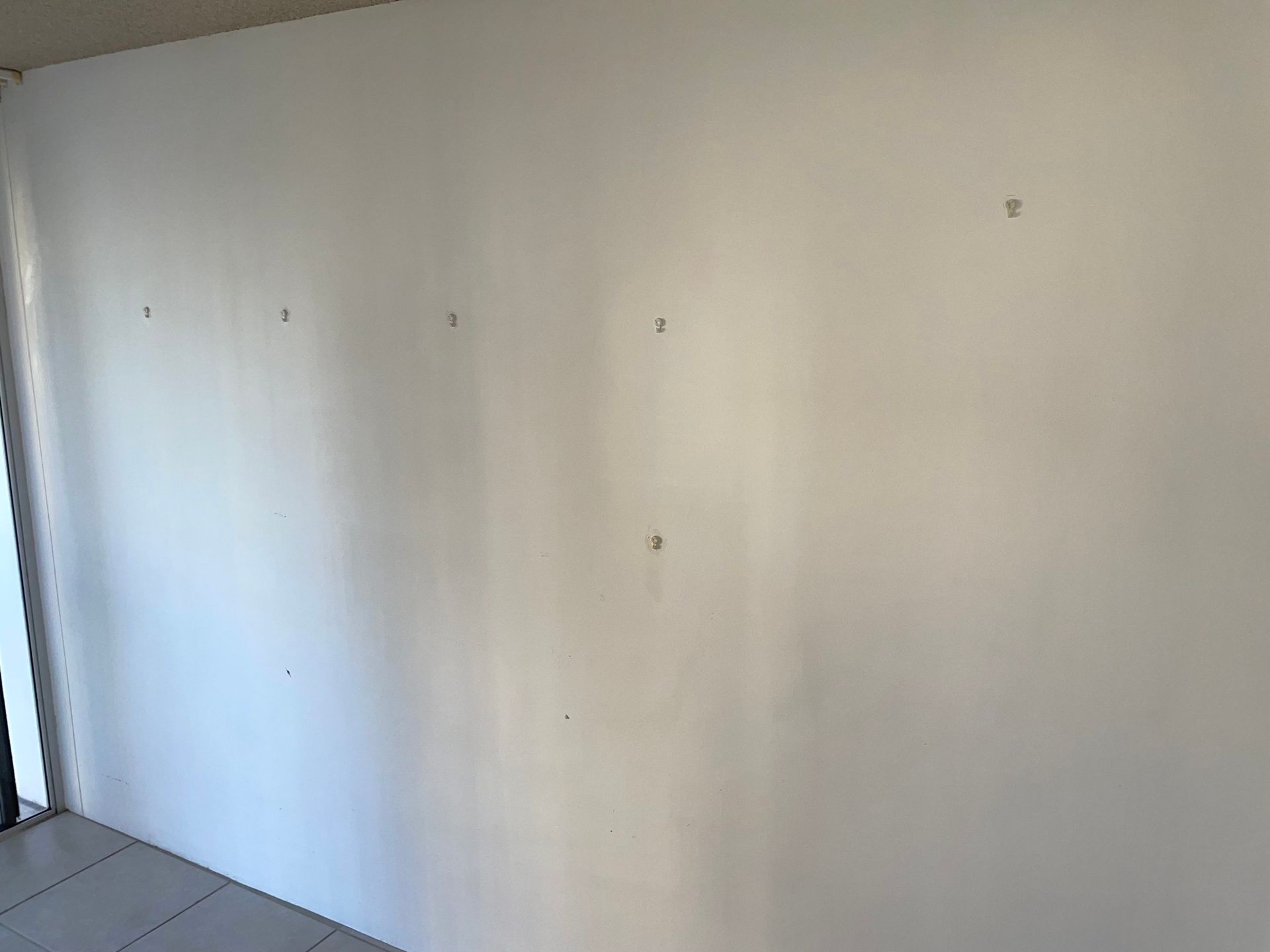 White wall with small holes, possibly for hanging items, inside a room.