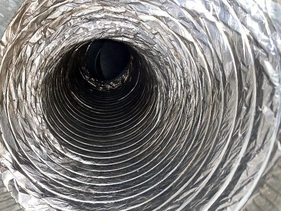 Inside view of a flexible, metallic air duct. Spiraling interior with a dark center.