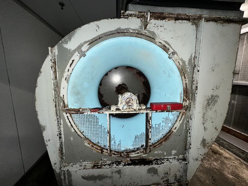 Large industrial fan with a blue interior, rusty metal frame, and protective grate.