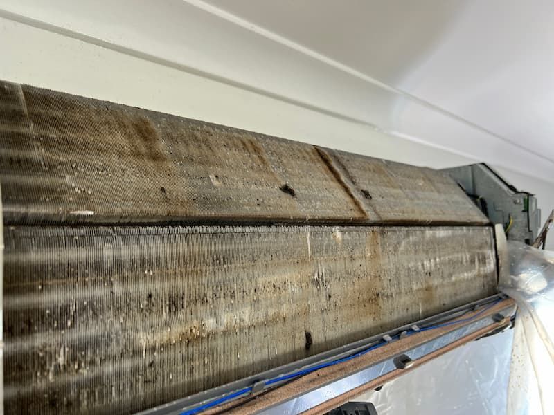 Dirty air conditioning unit, close-up. Dust and debris cover the cooling fins.