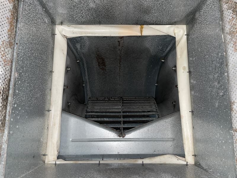 Inside view of a metal HVAC unit with a filter frame and a metal grate visible.