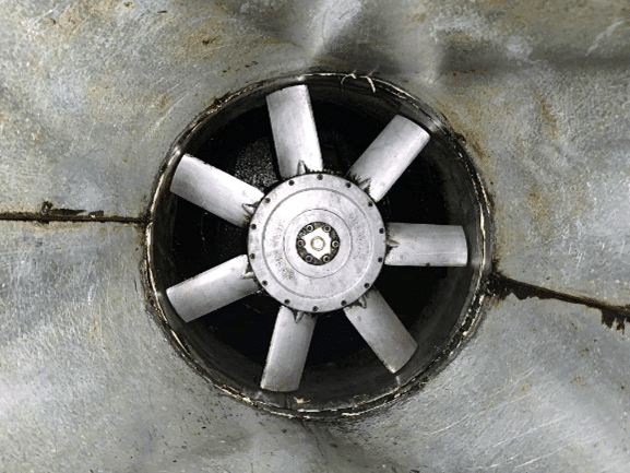 Fan blades inside a circular opening, set in a metallic surface.