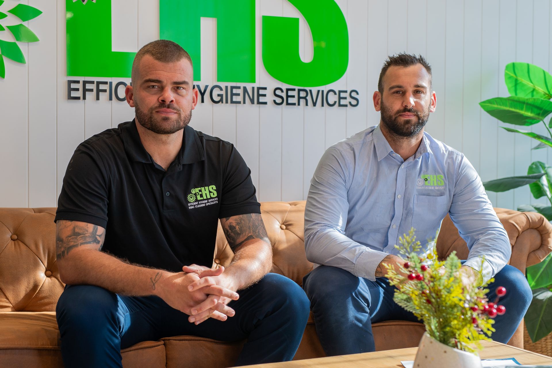 Two men sit in front of a green and white logo that reads “LHS Efficient Hygiene Services”.