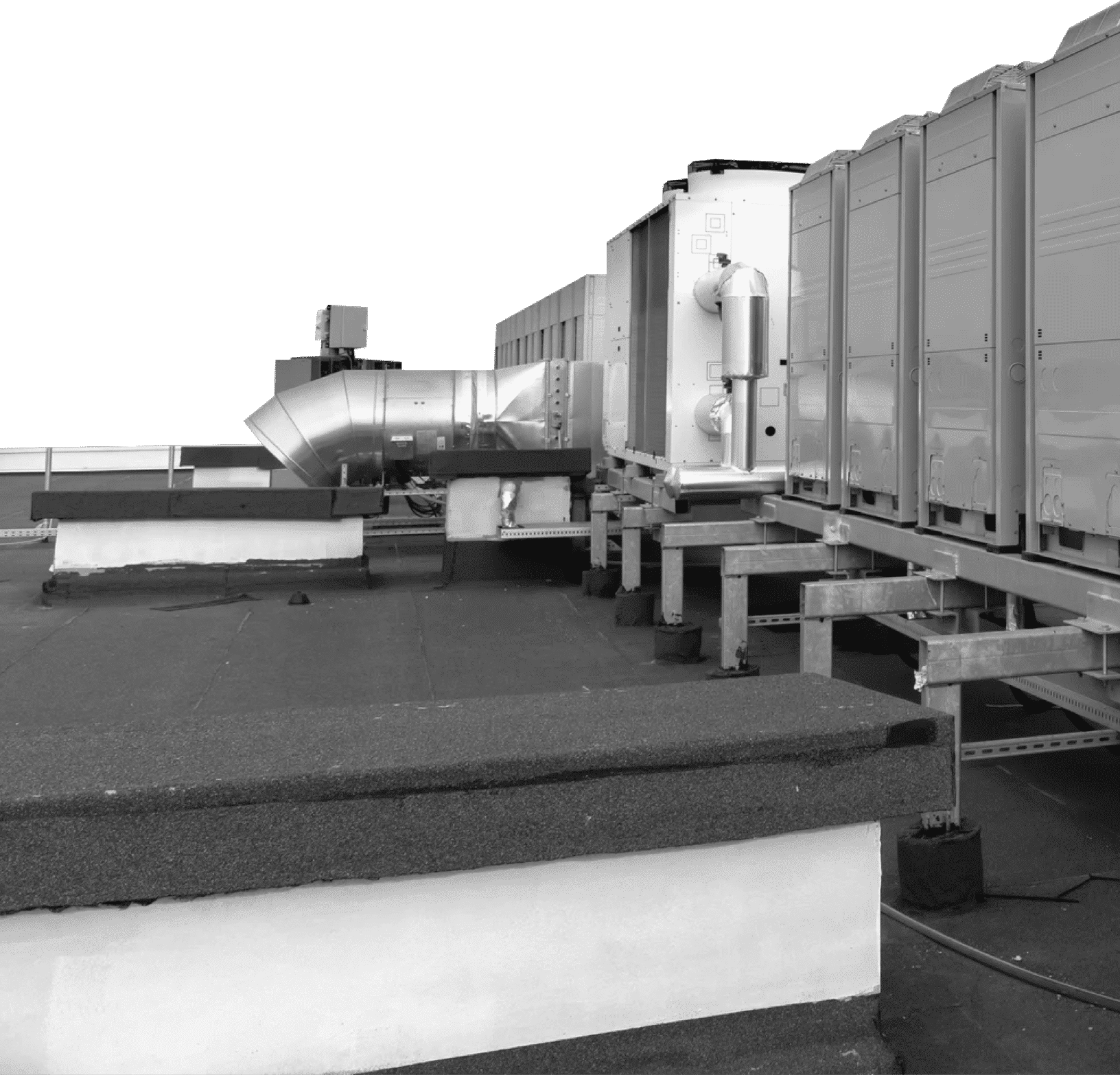 Rooftop with HVAC equipment and ductwork, supported by metal frames, against a bright sky.