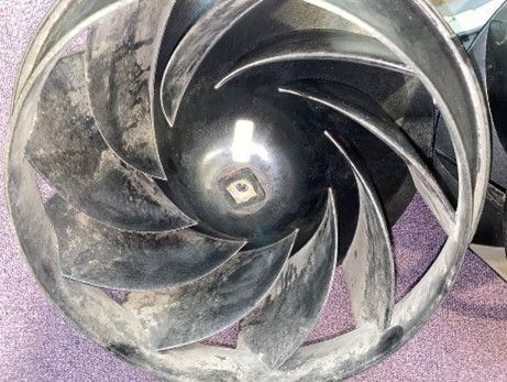 Black impeller with curved blades, covered in debris.