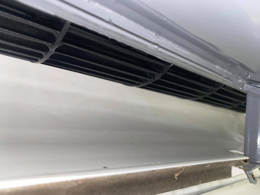 Black air vent within a white compartment, likely part of an appliance.