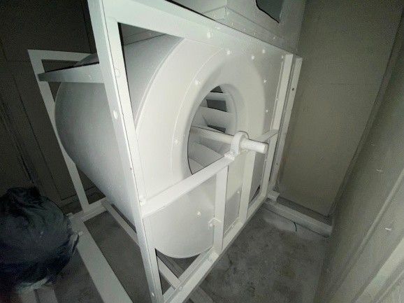 White industrial fan inside a white metal frame, set in a room.