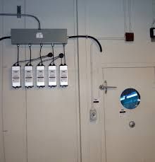 Electrical box with hanging devices on a wall next to a door with a porthole window.