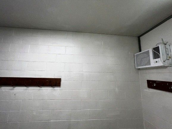 White cinder block walls with dark brown coat racks and a white air conditioner.